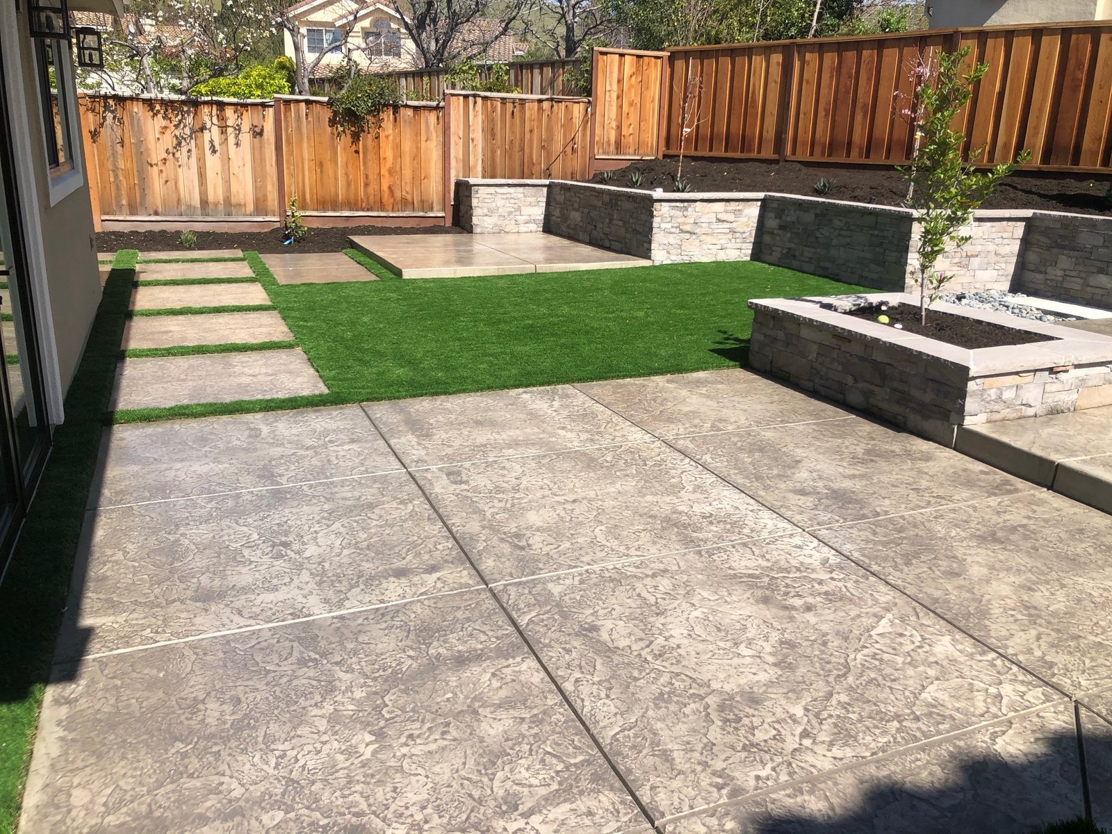 Concrete patio with retaining walls and artificial turf