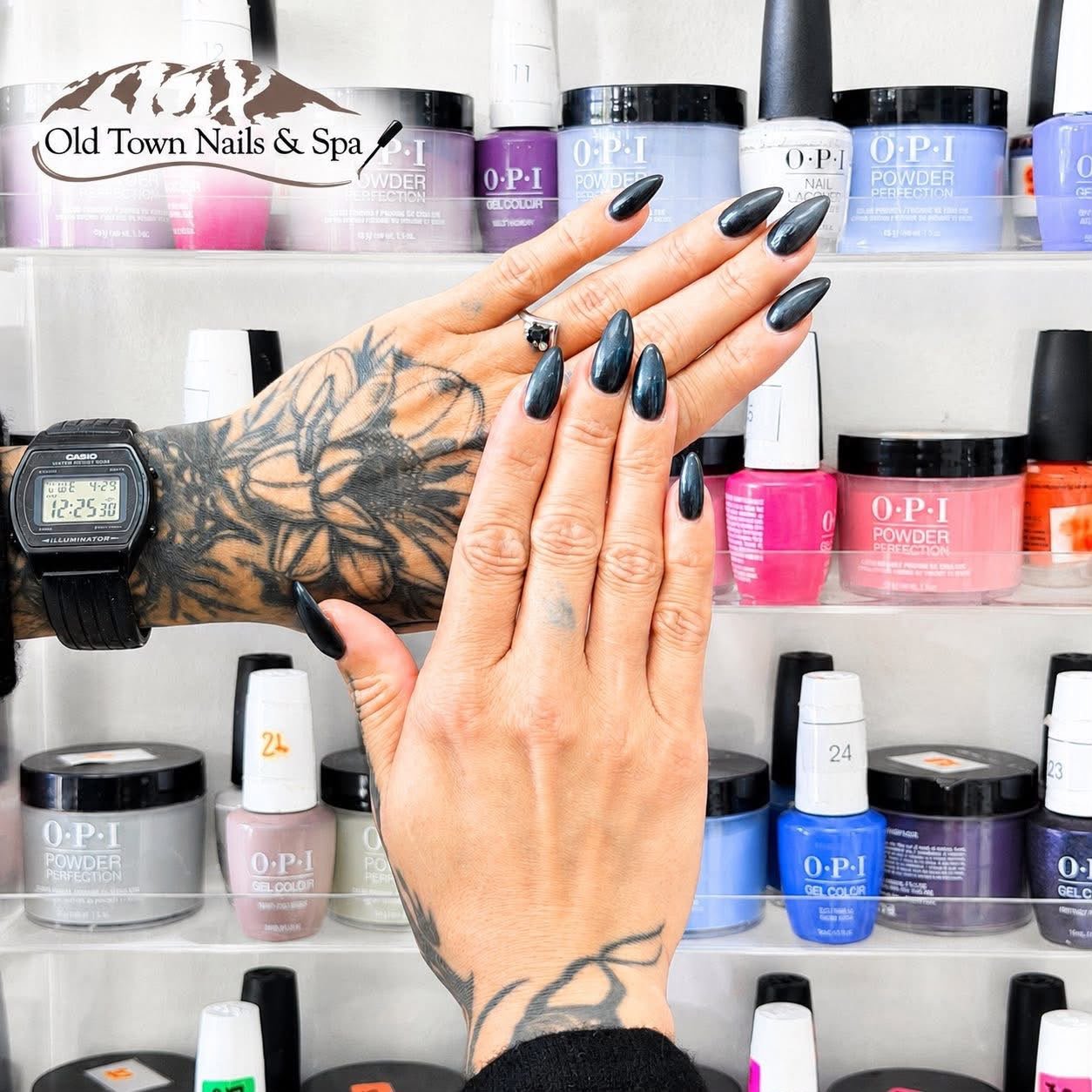 Long glossy black stiletto nails in front of OPI polish at the salon