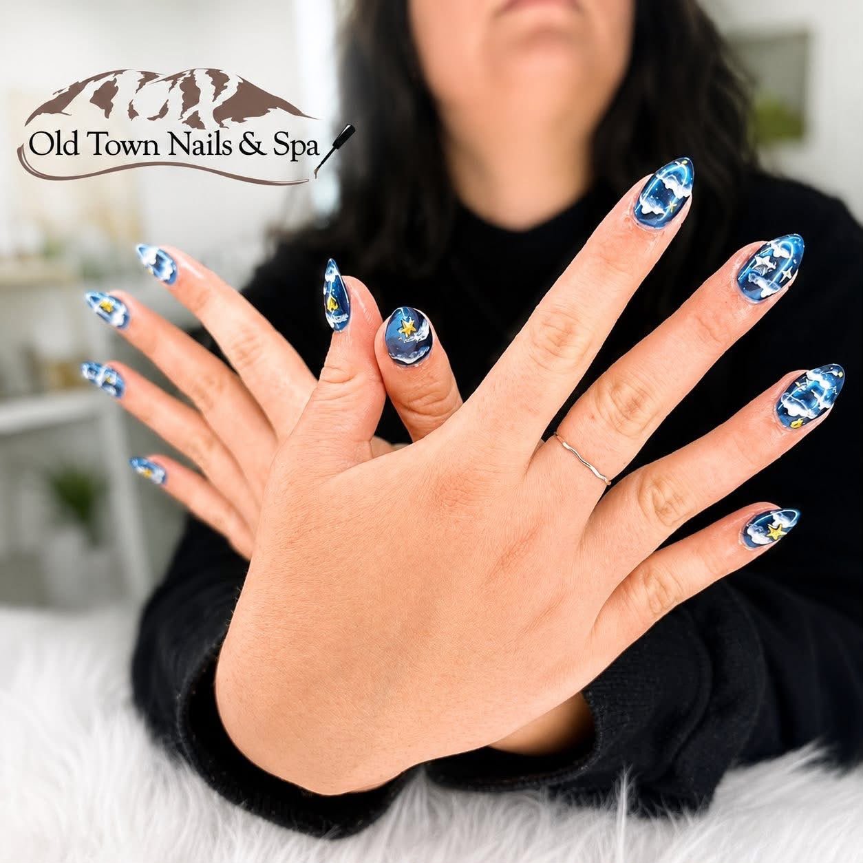 Blue sky nail art with clouds and gold stars on almond nails