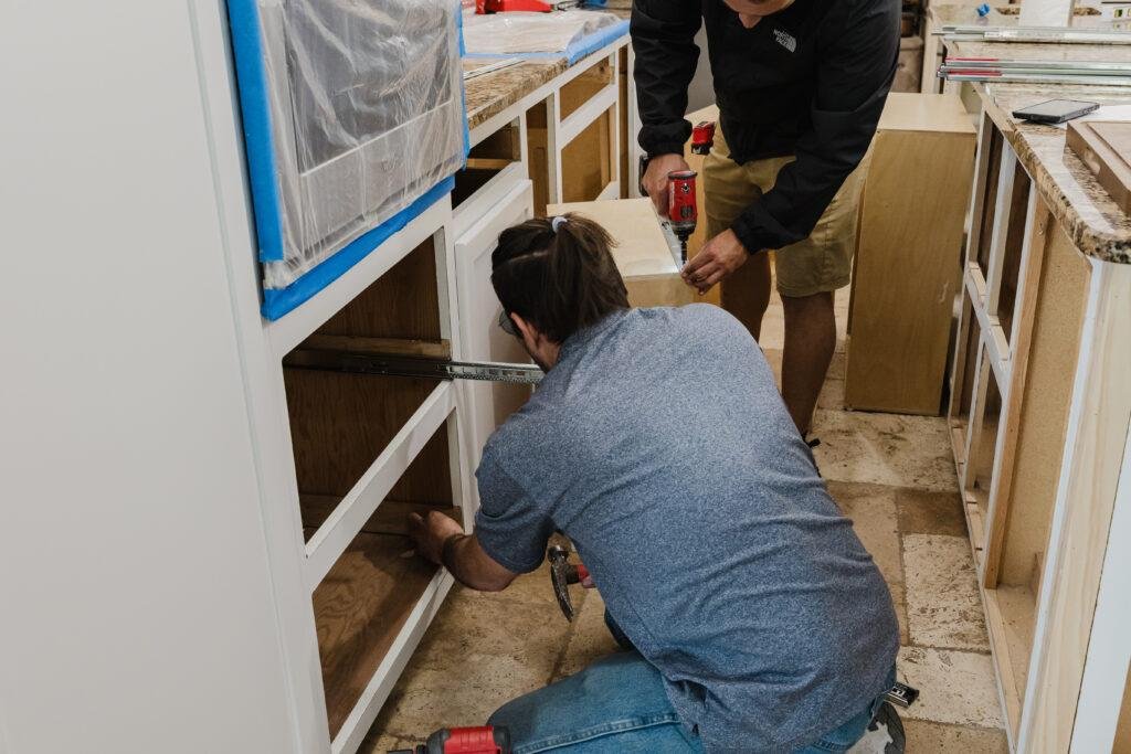 Installers fitting a refaced cabinet drawer during a kitchen refacing project
