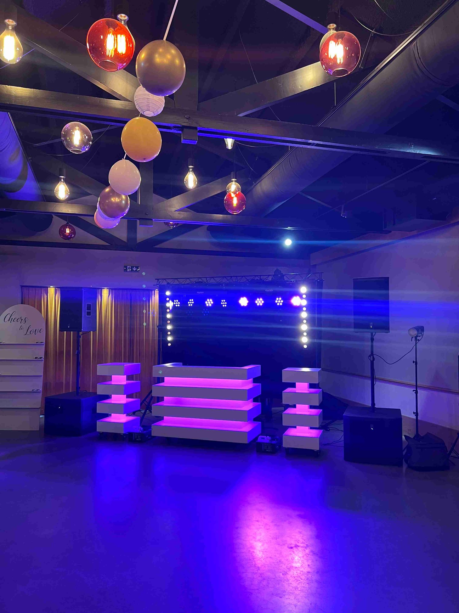 Event space with DJ setup, ambient lighting, and decorative balloons