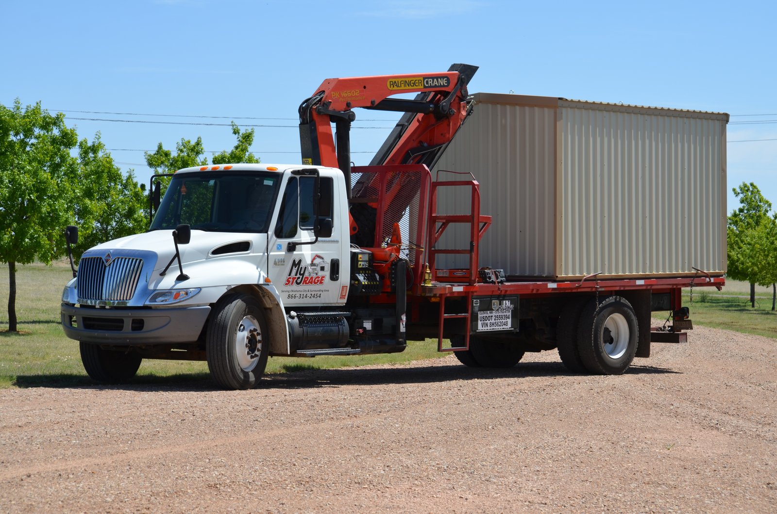 My Storage specialized crane delivery truck relocating a portable storage building