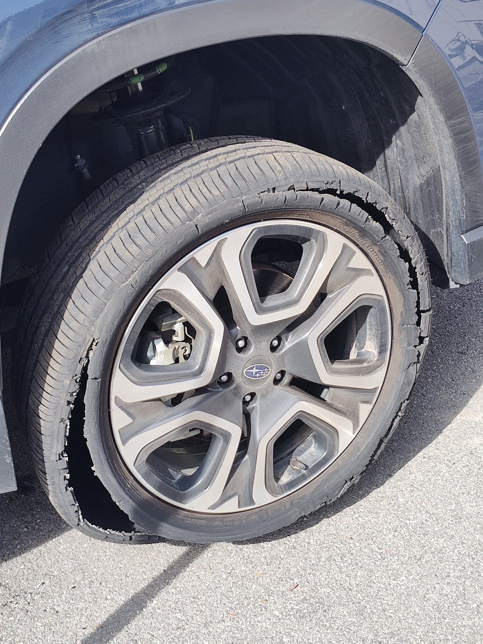 Severely blown out tire sidewall on a Subaru requiring immediate roadside replacement
