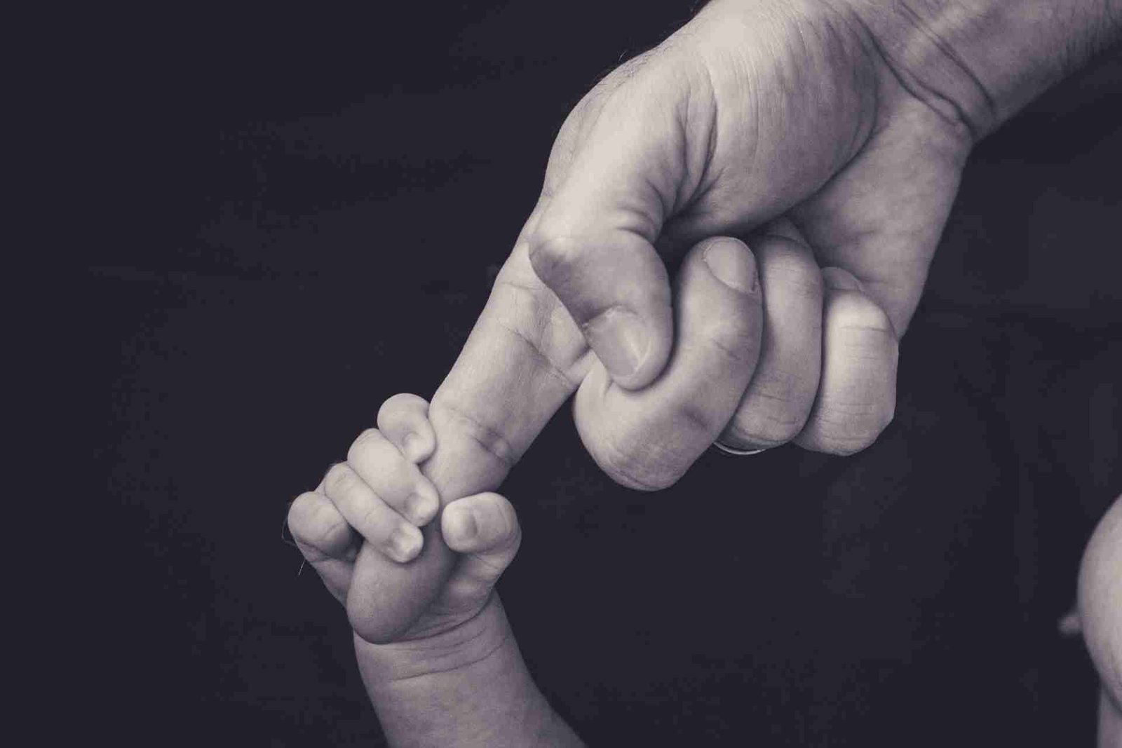 Newborn baby hand holding an adult finger