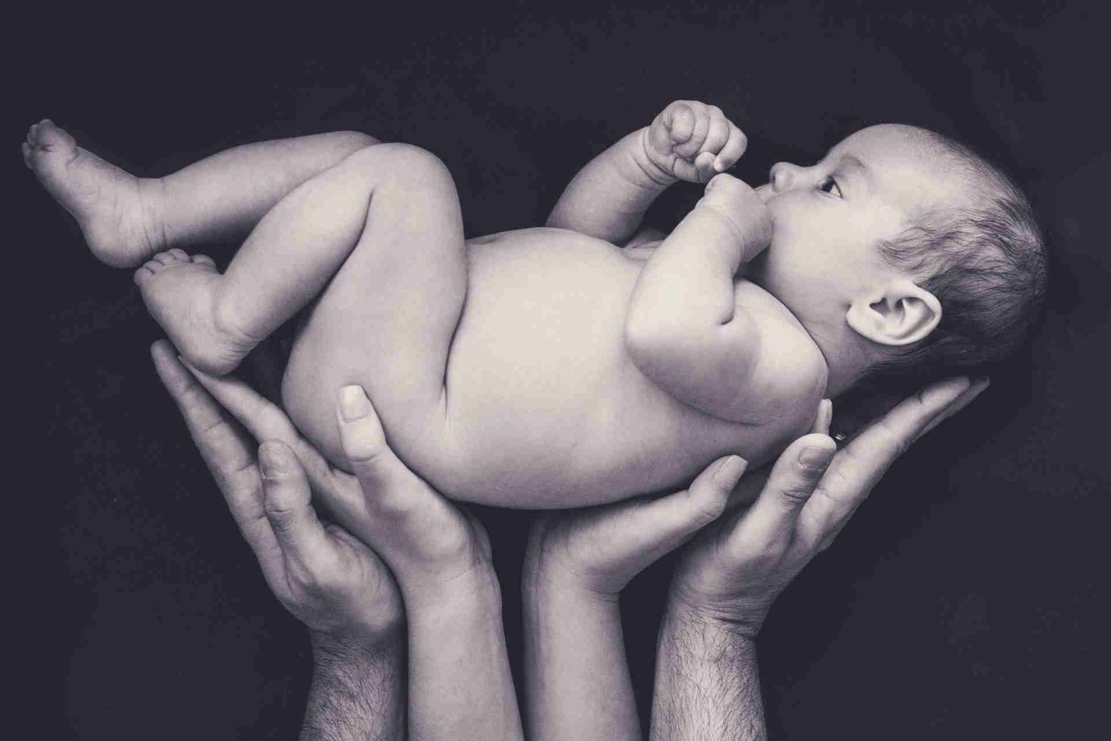 Black and white photo of baby held in hands