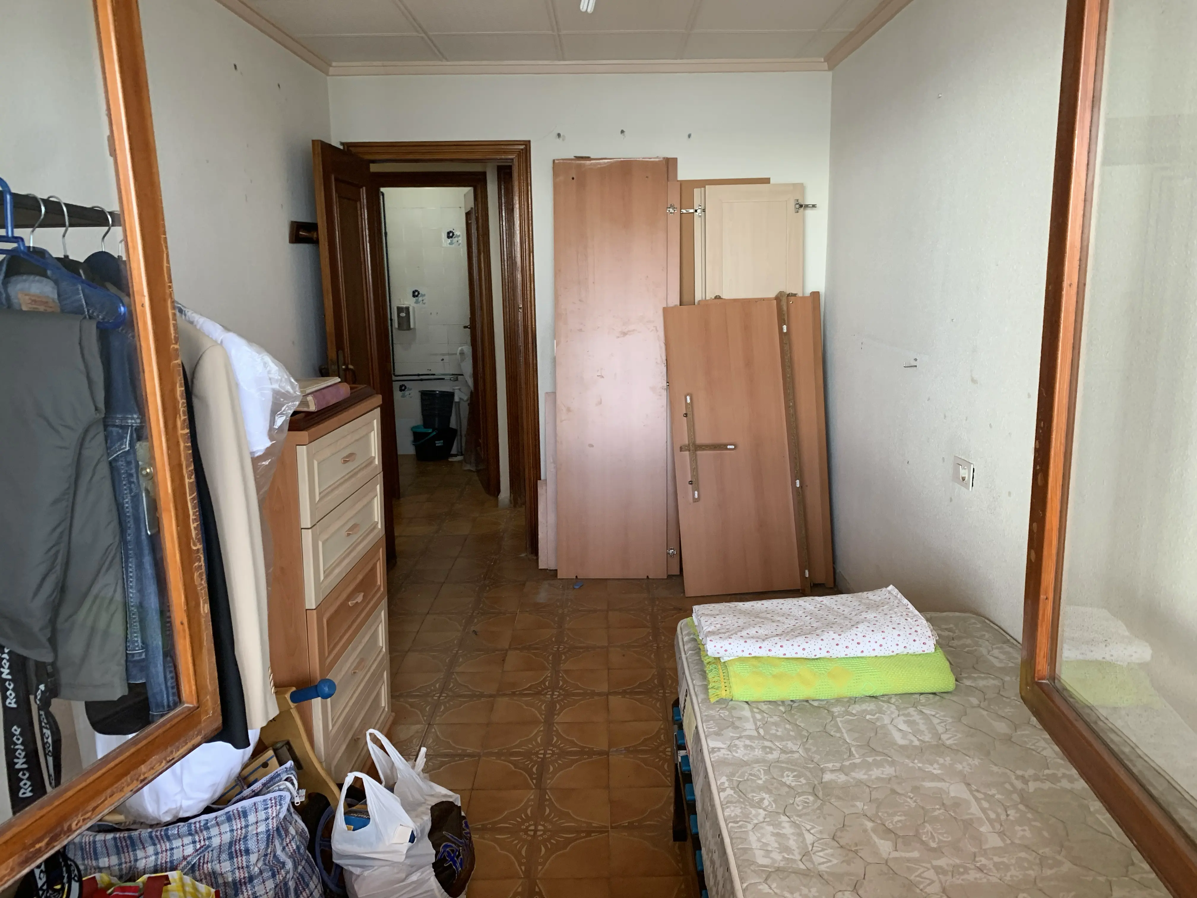 Bedroom before renovation &mdash; dated dark wooden bed frame, heavy curtains and worn carpet
