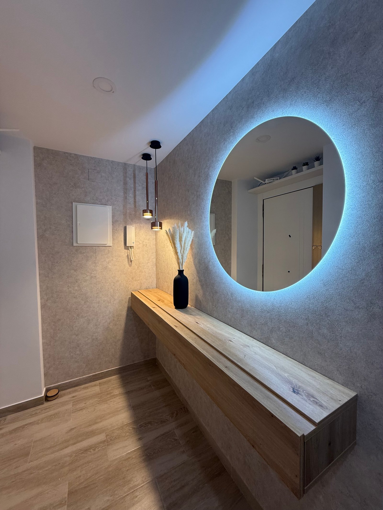 Entrance hallway with wooden counter and round illuminated mirror