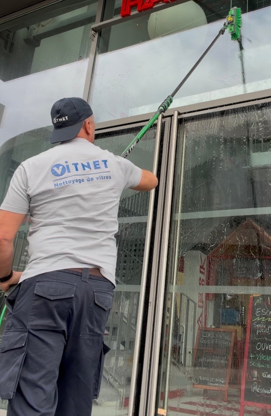 Professionnel nettoyant la vitrine d'un commerce à Bordeaux avec une raclette