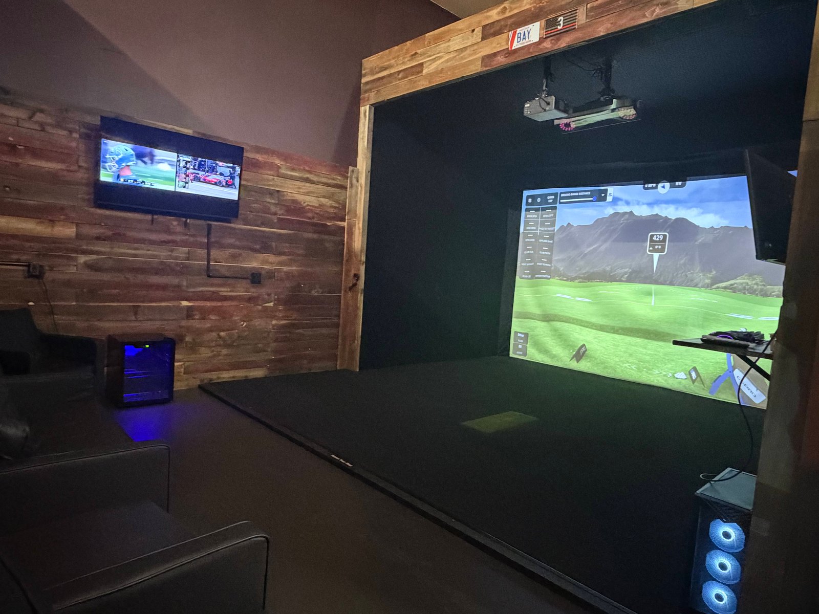 Mulli Den indoor golf simulator bay with a virtual fairway on screen
