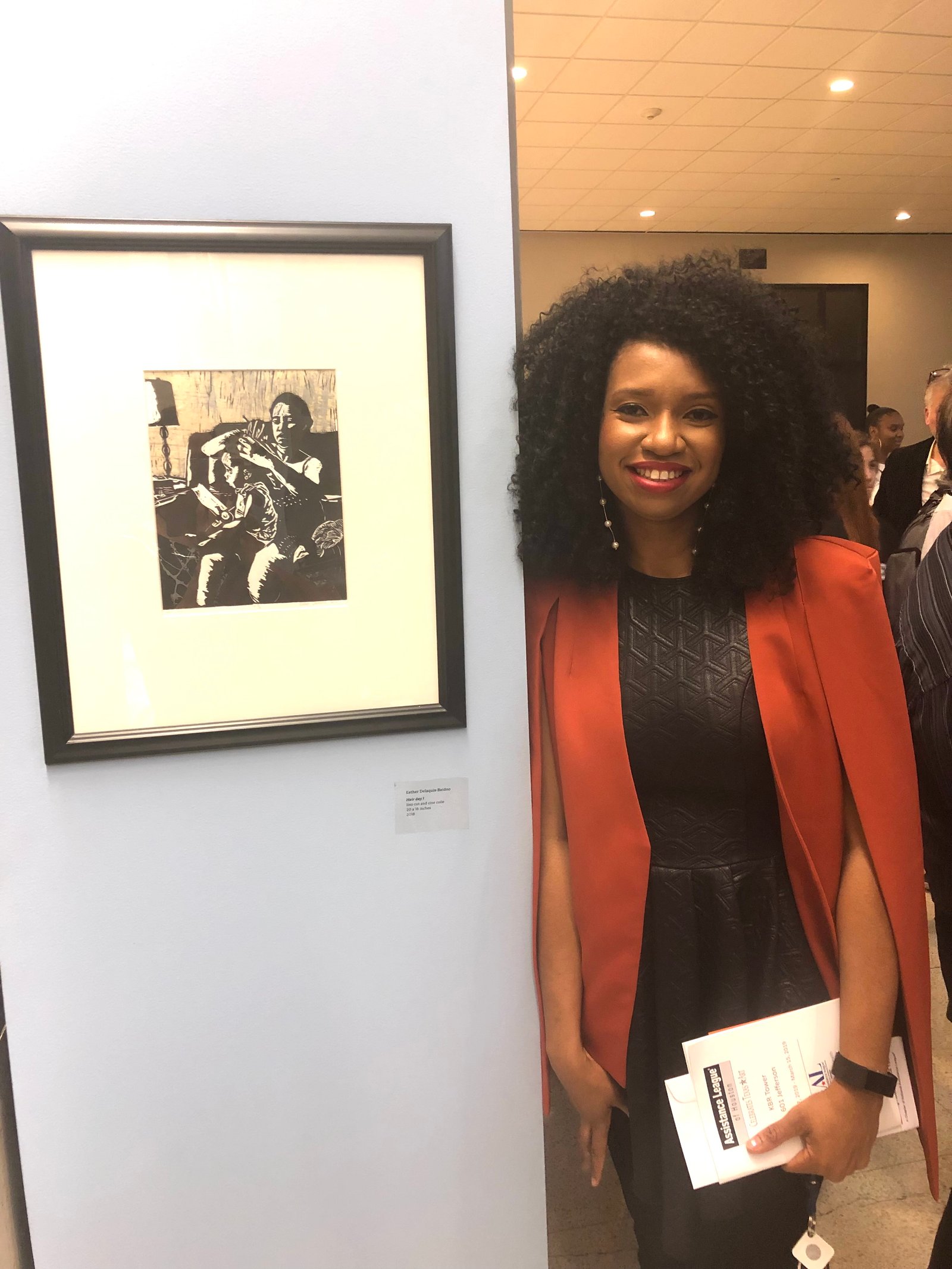 Esther Delaquis-Baidoo standing beside her artwork at an art exhibition