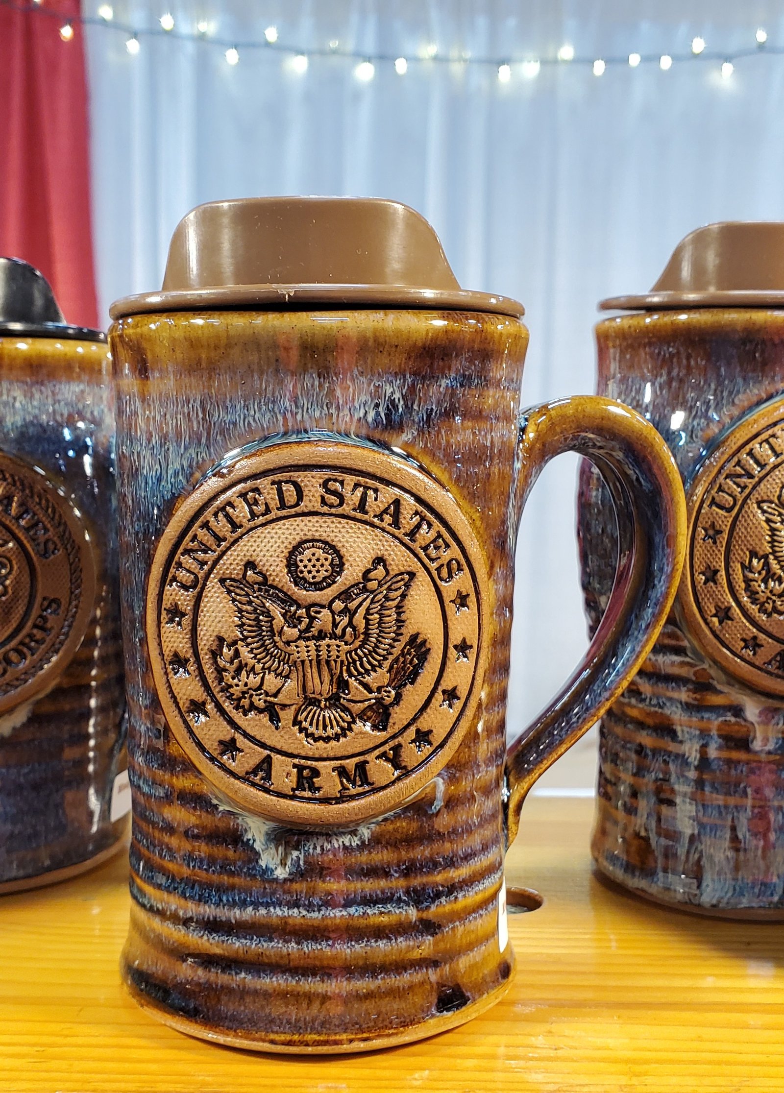 Ceramic beer steins with United States Army seal and emblem, featuring rich brown glaze with detailed metalwork details