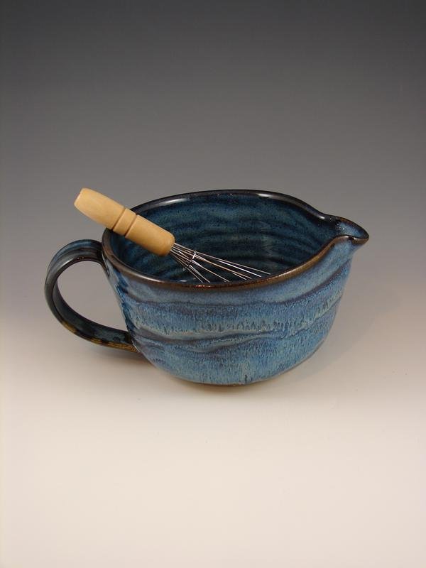 Blue pottery vessel with wooden whisk showing deep blue and brown tones