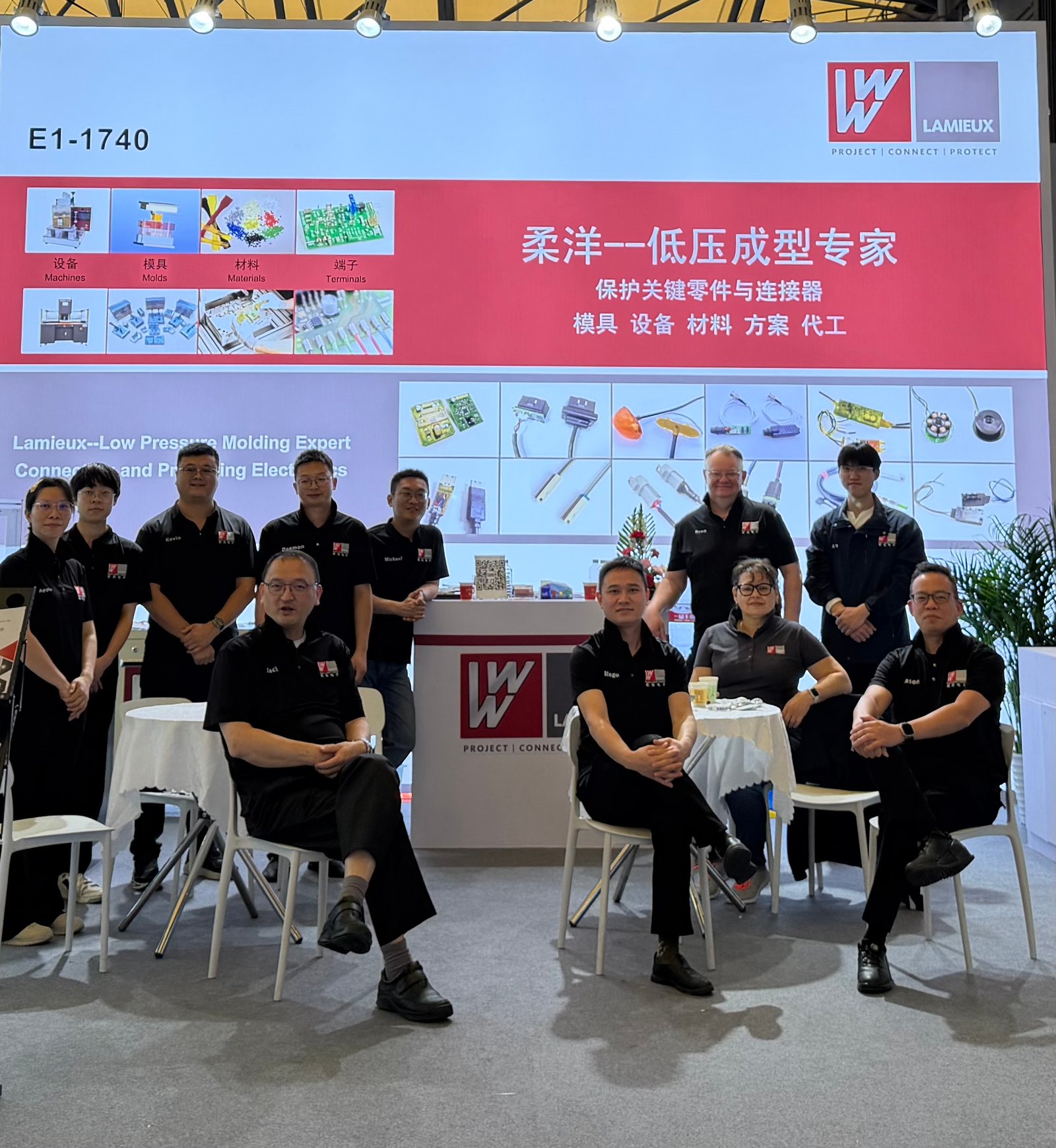 Lamieux Electronics team at trade show booth with company branding and low pressure molding expertise