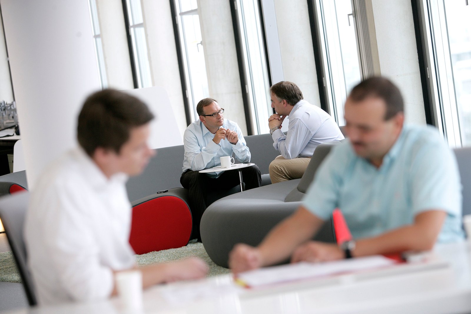 Documentary photography of colleagues discussing work together in a bright office by Doug Marke.