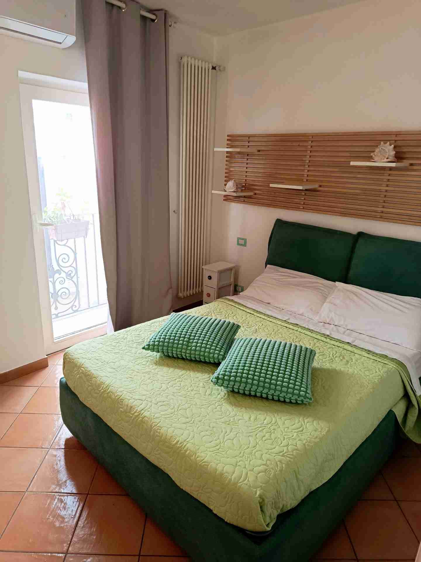 Master bedroom with a green headboard and a balcony