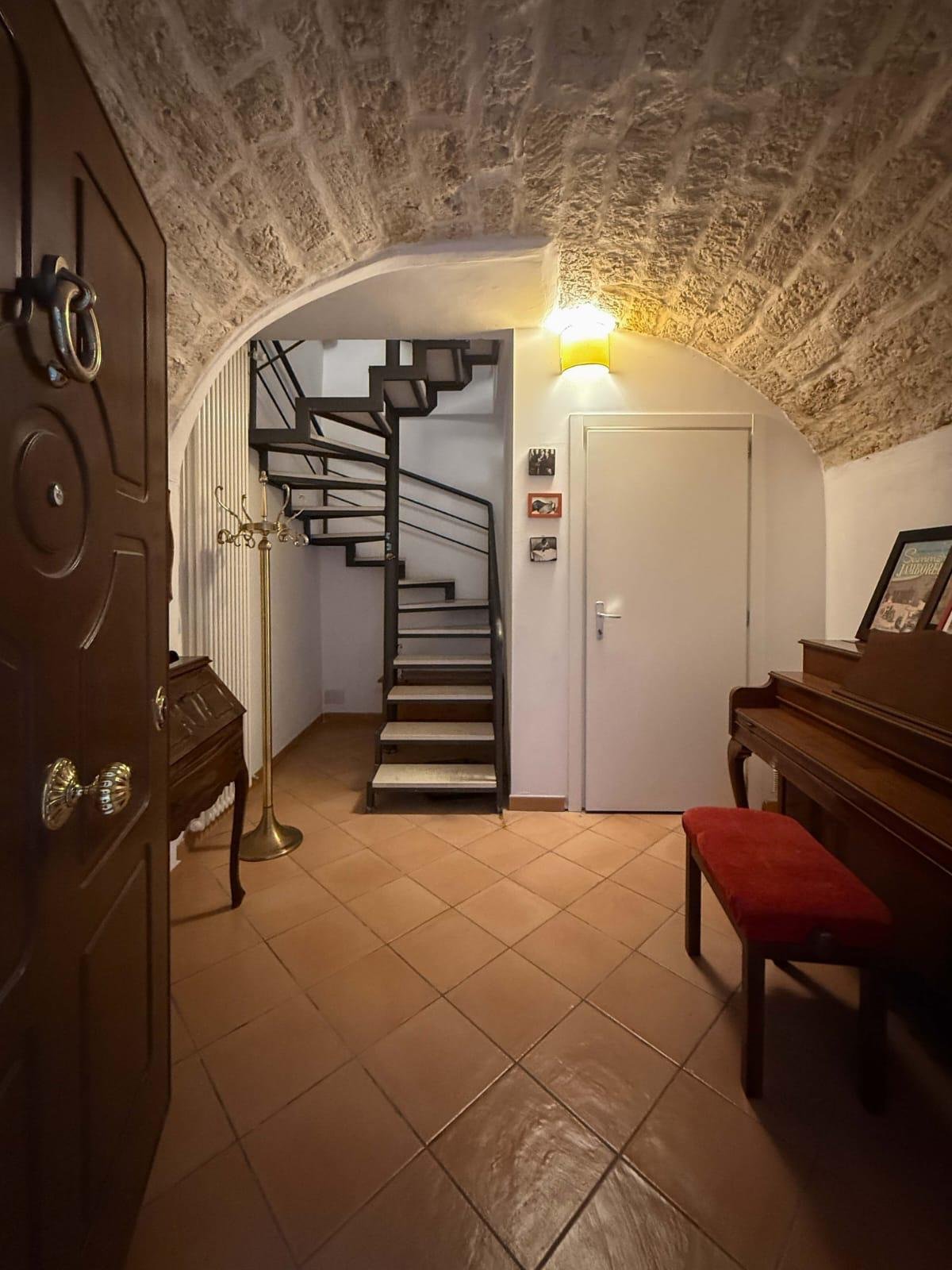 Stone-vaulted entrance with a piano and a spiral staircase