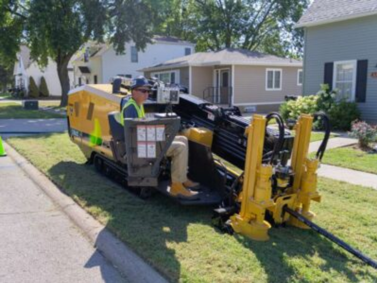 Vermeer directional drilling rig boring for underground fiber conduit at an active utility site