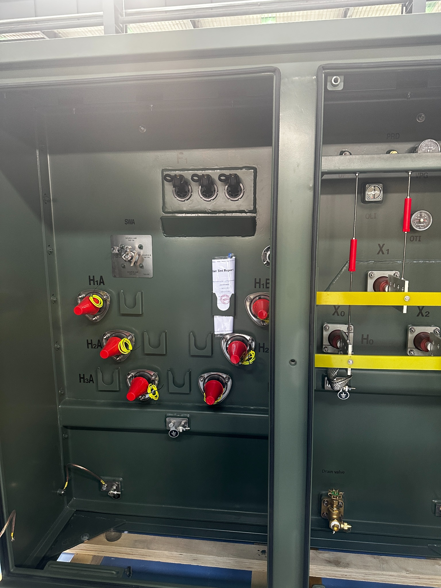 Open pad mounted transformer compartments showing bushings terminals gauges and test report documents