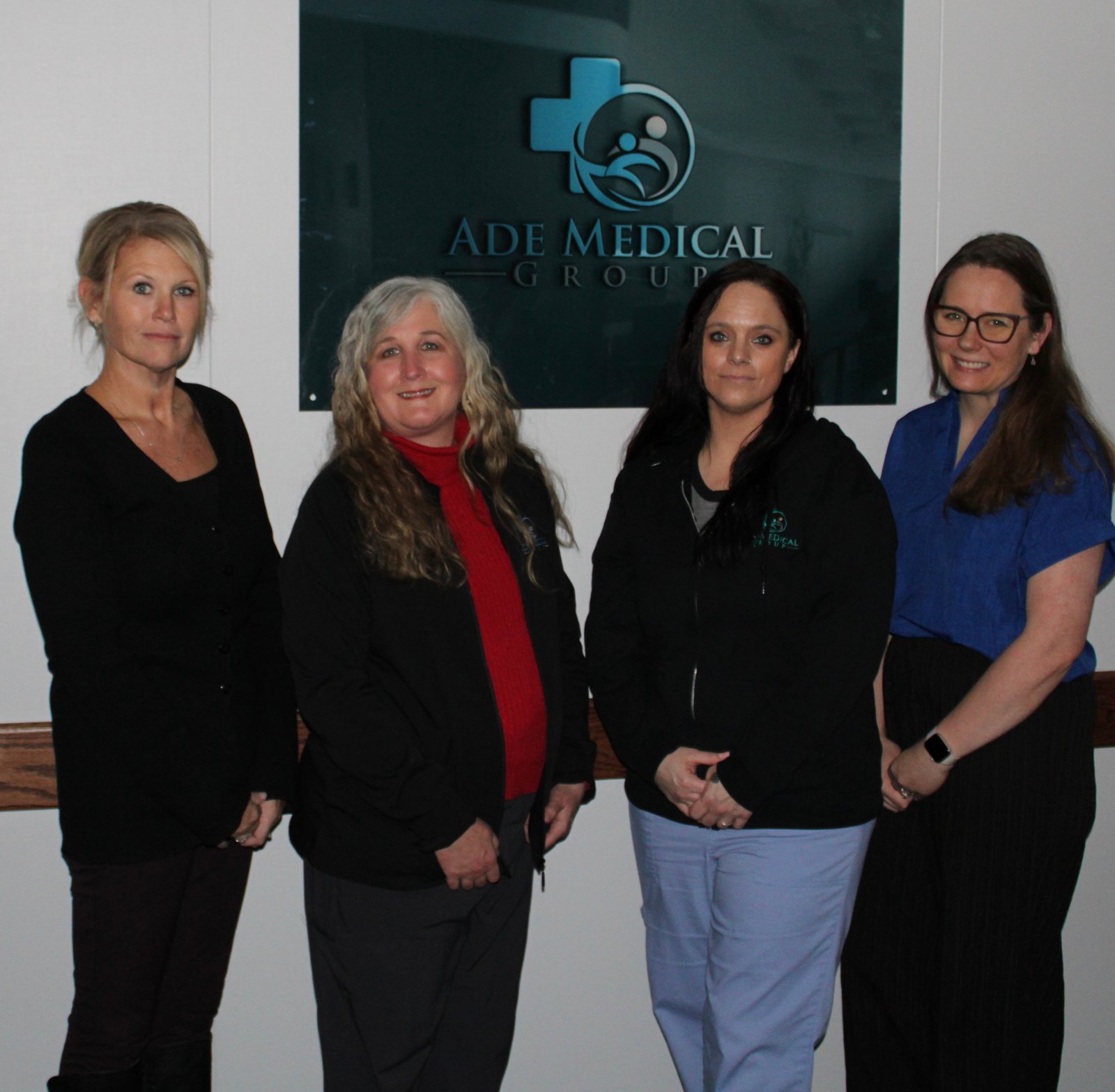 Four female team members in professional attire in front of ADE Medical ...